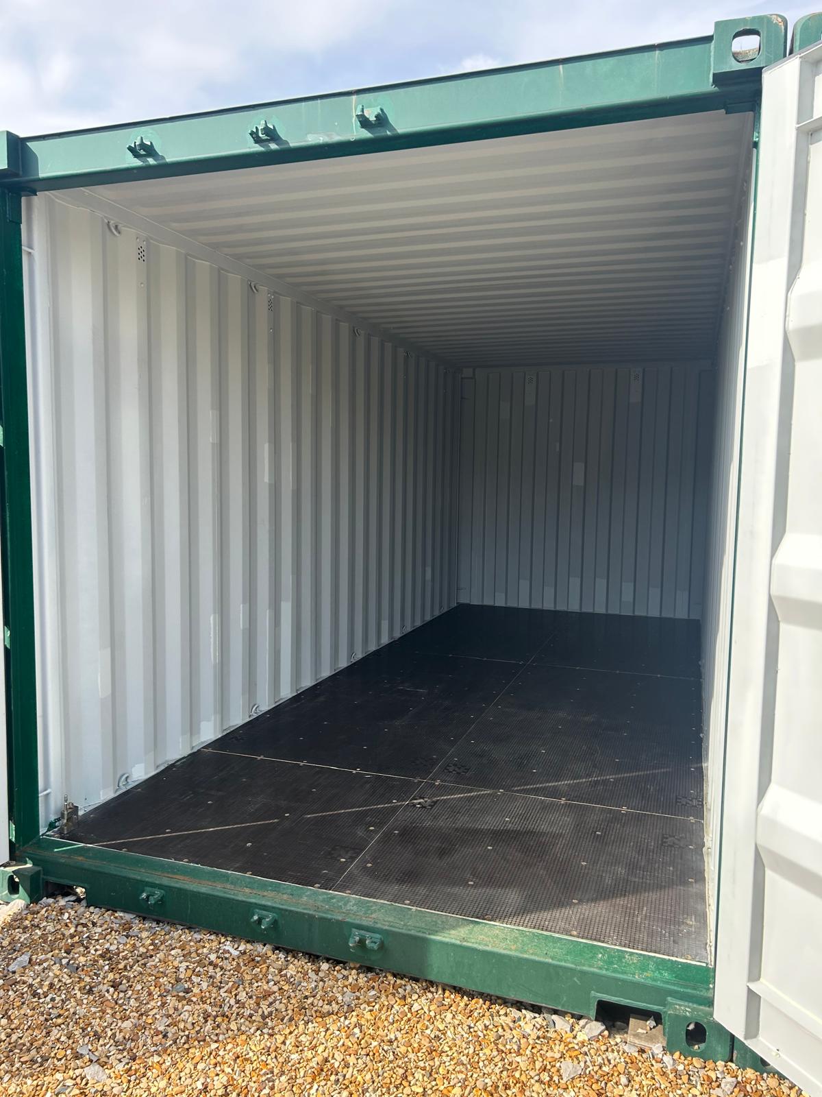 Empty green container storage unit with its doors open, showing pale steel walls and a dark hardwearing floor